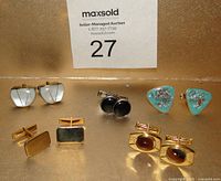 Five pairs of vintage cuff links arranged in two rows: white enamel rectangular, round black button, gold filled rectangular, agate stone with gold frame, turquoise enamel triangular with metallic flecks.