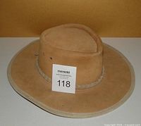 Tan brown suede leather hat with wide brim and braided band with metal star concho, shown from the front angled view.