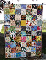 Full view of colorful patchwork quilt featuring assorted squares with children's patterns like kites, animals, and musical notes.