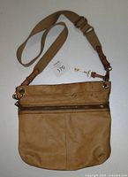 Front view of the Fossil tan buckskin leather crossbody purse with visible zipper and adjustable strap.
