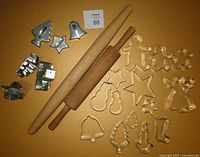 Photo showing two wooden rolling pins and 20 metal cookie cutters with Christmas shapes including trees, stars, bells, gingerbread men, candy canes and angels.