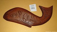 Front view of the carved fish wall plaque showing Haida style engravings and reddish-brown wood finish with some scuffs.