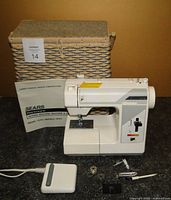 Kenmore sewing machine in front of woven sewing basket with foot pedal and sewing accessories arranged in front