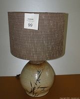 Full view of the upholstered fabric shade and ceramic lamp base with bamboo design.