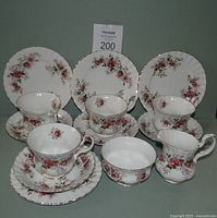 14 piece set including cups, saucers, side plates, creamer, and open sugar bowl displayed together showing floral pattern and gold trim