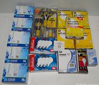Photo showing multiple boxes of GE 60 Watt, GE soft white 40 Watt, Sunbeam 40 Watt, Reveal 40 Watt light bulbs, a Spectro 50 Watt spot light bulb, and an opened bulb changing kit in clear packaging.