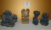 Front view of four gargoyle resin pieces: three gargoyle figurines and two candle holders showing detailed sculptures.