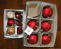 Lot contents show sets of nine ornaments in boxes on wooden floor: 5 large balls on right, 5 smaller assorted on left.