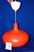 Front view of the orange metal ceiling light pendant showing shape and color