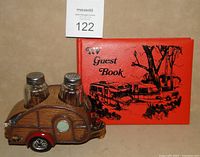 Photo showing the novelty trailer salt and pepper set with clear glass shakers placed within the trailer body, next to the RV guest book with printed front.