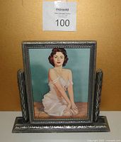 Front view of the 1940's pin-up print inside the carved Art Deco swing frame showing the featured woman and frame design.