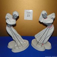 Front and side view of two vintage chalkware dancers with grey faces and white outfits, standing 11 inches tall, with slight paint knicks.