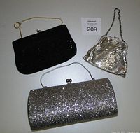 Photo showing three vintage purses: silver glitter rectangular clutch, small silver metal mesh purse with chain, and black hand-beaded clutch with gold wire handle.