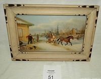 Front view of the framed print depicting horse and sleigh winter scene with beige frame with dark spots