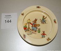 Top view of the vintage children's bowl showing the central scene of a bunny painting at an easel and smaller animal figures around the rim.