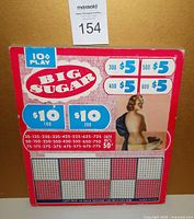 Front view of vintage 'Big Sugar' punch board game with prize amounts, 10 cent play indication, and pin up girl graphic.