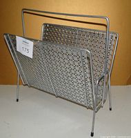 Front angle of the vintage silver metal magazine stand showing perforated design and handle