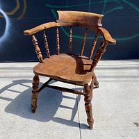 Front angle view of antique captain's bow seat smoker's chair showing seat, backrest and armrests