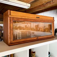 Front side view of the oak barrister bookcase showing the glass panel and brass plaque on top front with surrounding area.