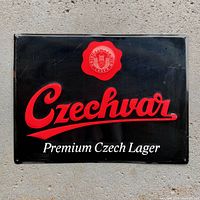Full view of Czechvar tin beer sign showing brand logo and slogan on black background.