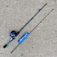 Full view of the two-piece blue and black Shakespeare Amphibian fishing rod with baitcasting reel and original Shakespeare tag visible.