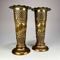 Front view showing the detailed brass embossing and scalloped rims of the two vintage brass bud vases.