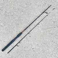 Full view of the two-piece fishing rod laid out on concrete showing the handle and rod sections separately.
