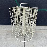 Front view of white wire spinning retail display rack showing basket and base.