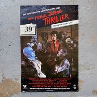 Full view of the 1983 Michael Jackson Thriller video promotional poster featuring the artist in red surrounded by zombies with large text and pricing sticker.