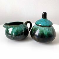 Photo showing ceramic cream pitcher and sugar bowl set with drip glaze.