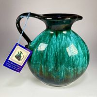 Photo of front and side of Blue Mountain Pottery jug showing bulbous body and drip glaze in green and blue with attached original tag