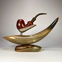 Front view of the vintage bull horn pipe stand holding the estate pipe, showing the polished natural horn materials and wood pipe bowl with black bent stem.