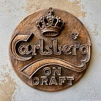Full view of circular faux carved wood Carlsberg bar sign with raised lettering and crown detail.