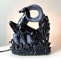 Front view of the vintage black ceramic lamp depicting a prancing gazelle with detailed curved horns and grass base.