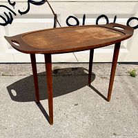 Side view of the wooden tray table with removable tray top, showing tapered legs and oval wooden tray with built-in handles.