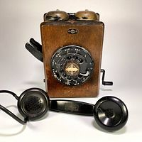 Front view of vintage 1950's Northern Electric wall telephone with wooden case, rotary dial, and unified handset placed in front.