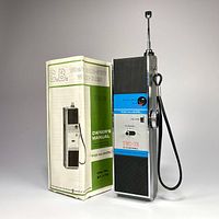 Front view of the Realistic TRC-75 CB radio and its owner's manual standing upright, with the extendable antenna fully extended.