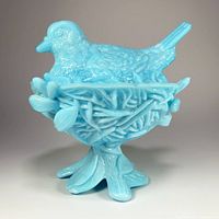 Side view showing the entire bird figurine on nest base with detailed twig and leaf design.
