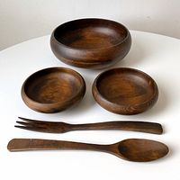 Full set of vintage wooden salad bowls with serving fork and spoon displayed on white surface.