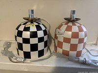Front view of two checkered ceramic table lamps without shades, one black and white and one light brown and white, with attached cords and switches.