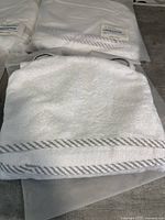 Four new white organic bamboo hooded baby towels folded, showing texture and striped border detail.