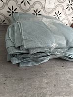 Stack of five folded light blue fleece blankets on countertop with decorative tile backsplash.
