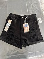 Front view of black distressed denim mom shorts with tags.