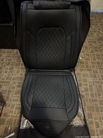 Black cushioned leather front car seat cover showing diamond quilted pattern on seating surface and smooth leather sides.