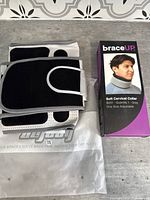 New XL adjustable back brace with velcro, folded showing front and back sides, resting on branded packaging.