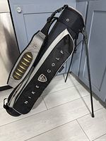 Side view of the Nike golf bag standing upright with attached stand and padded shoulder strap visible.