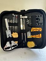 Top-down view of the entire watch repair kit laid open to show tools arranged neatly in the black zipped case.