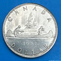 Reverse side of 1961 Canadian silver dollar coin showing canoe with two paddlers, date 1961, and 'CANADA DOLLAR' inscriptions.