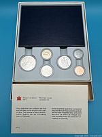 Top-down view of the set showing 6 coins inside a blue case with information brochure from Royal Canadian Mint.
