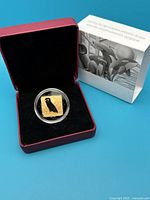 Photo of the coin inside red display box and outer protective sleeve.